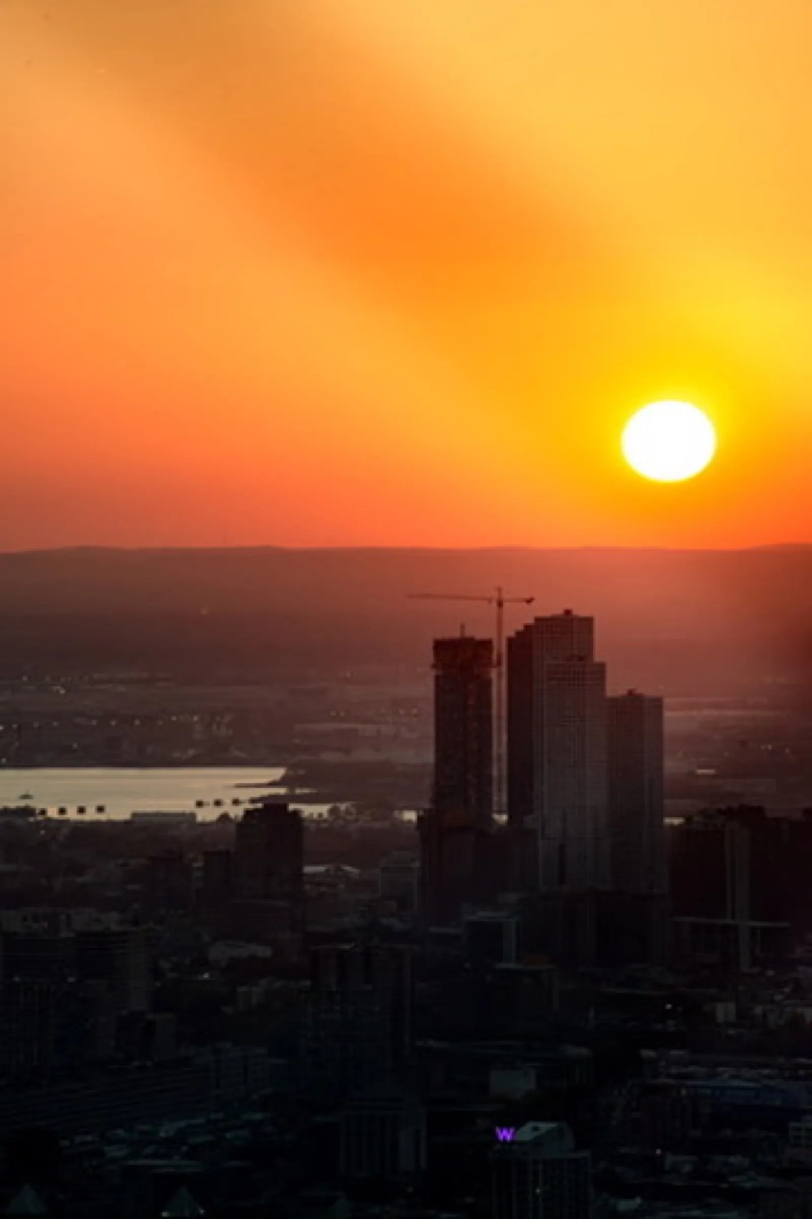 Sunset over city silhouette with bright sun