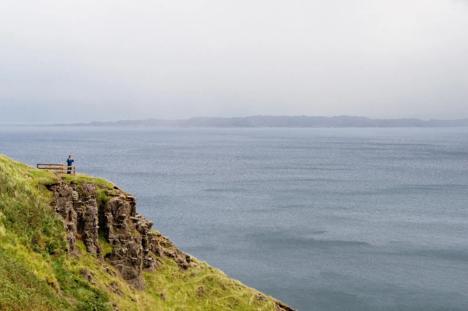 Person at rocky coastal cliff overlooking misty sea